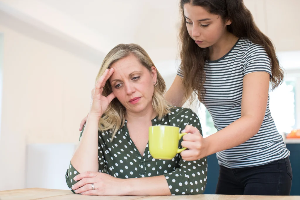 Young carer giving a worried lady a cup of tea in a yellow mug